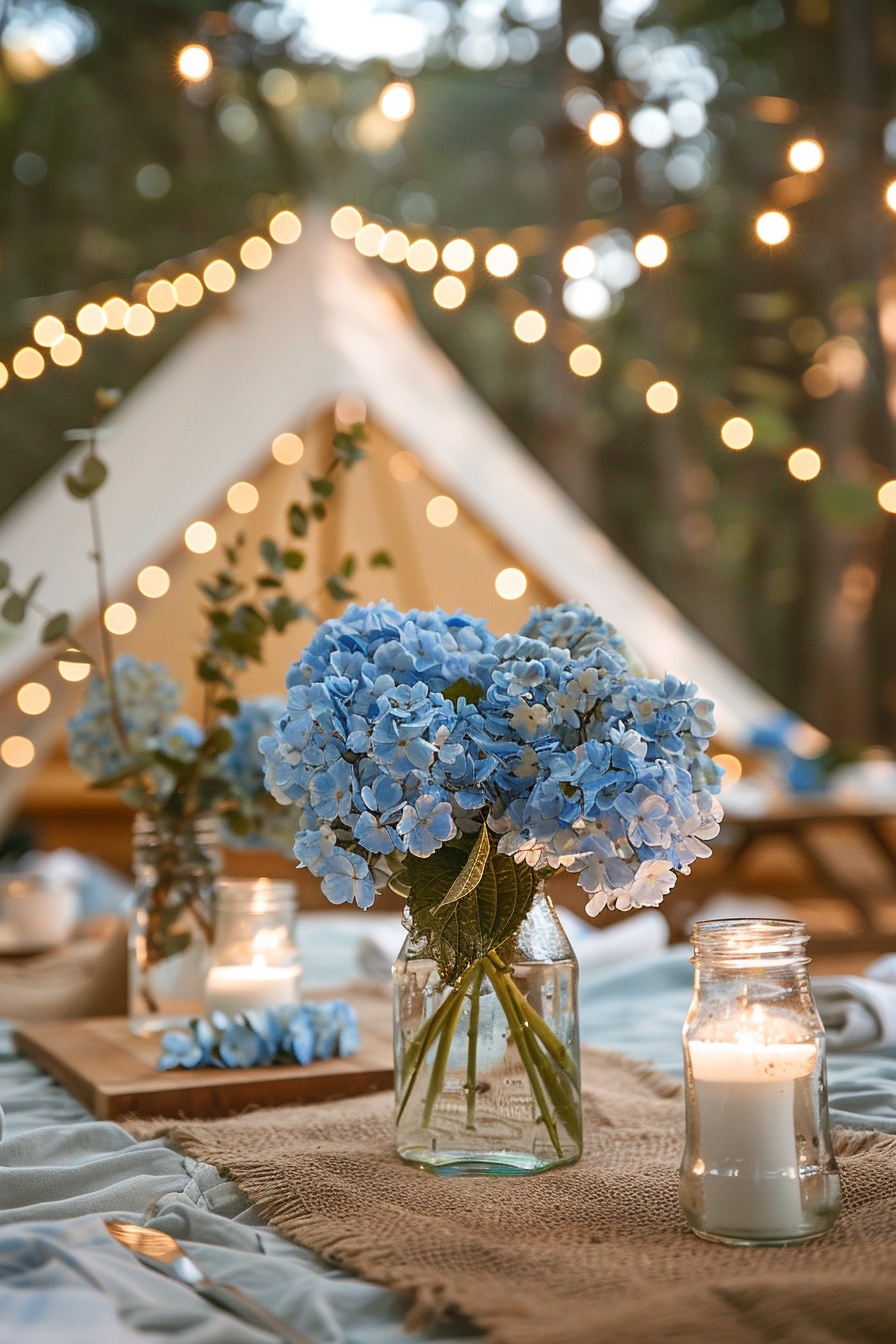 Glamping setup. Baby blue tent accented with string fairy lights and a vase filled with blue hydrangeas.