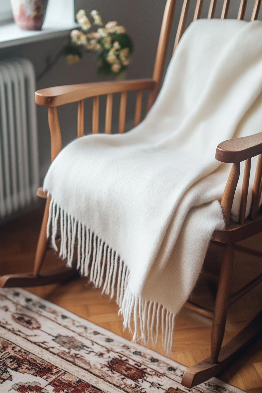 Fall bedroom decor. White wool blanket draped over a teak rocking chair.