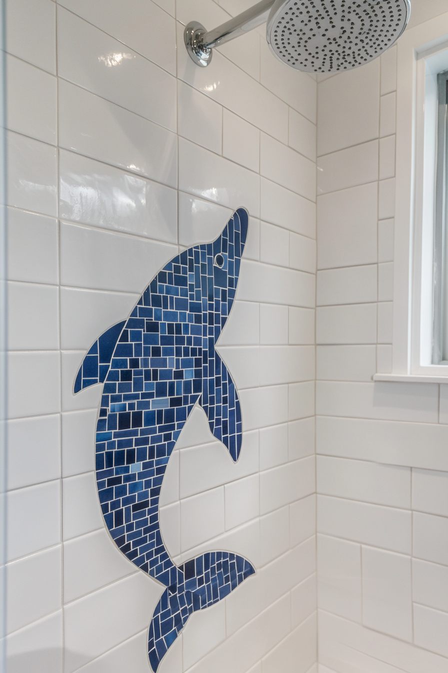 Tiny beach house shower. White tiles with navy blue dolphin shaped mosaic pattern.